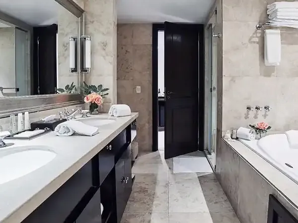 Luxurious modern bathroom with dual vanities, marble finishes, soaking tub and walk-in shower at Casco Antiguo hotel.