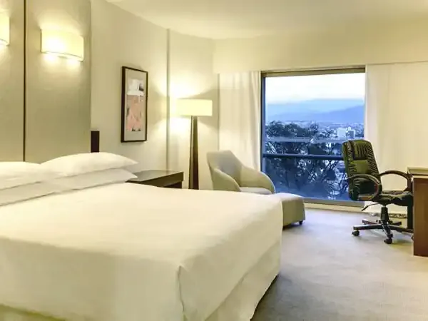 Modern hotel bedroom at Sheraton with panoramic mountain views and contemporary furnishings overlooking a Patagonian landscape.