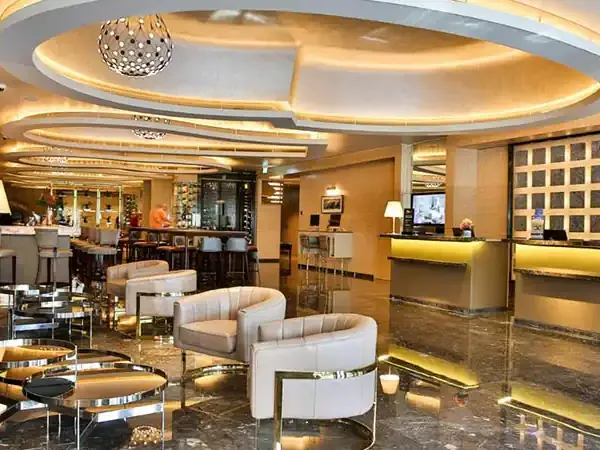 Luxurious modern lobby of Palladio Hotel featuring elegant cream furniture, warm gold ceiling accents, and polished marble flooring.