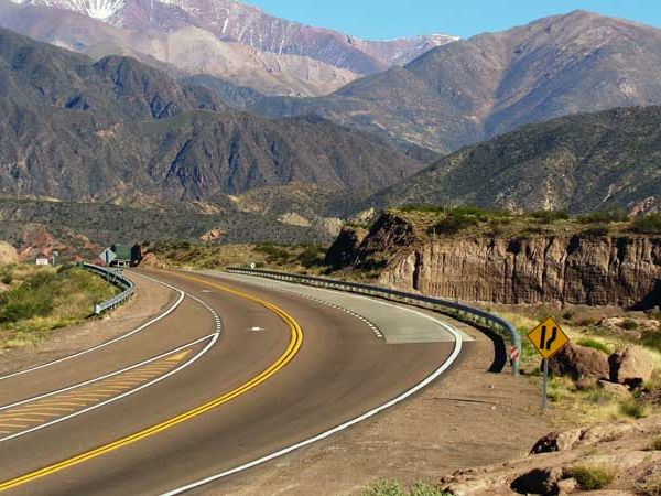 Scenic mountain road with yellow center lines curving through Andean valleys near Villavicencio, Mendoza.