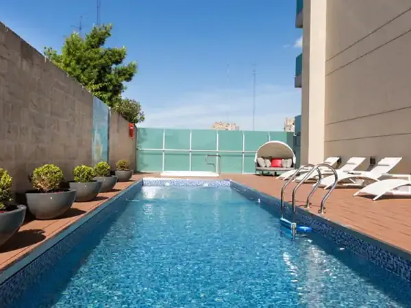 Rooftop pool at Palladio Hotel with loungers, mountain views, and modern architectural design.