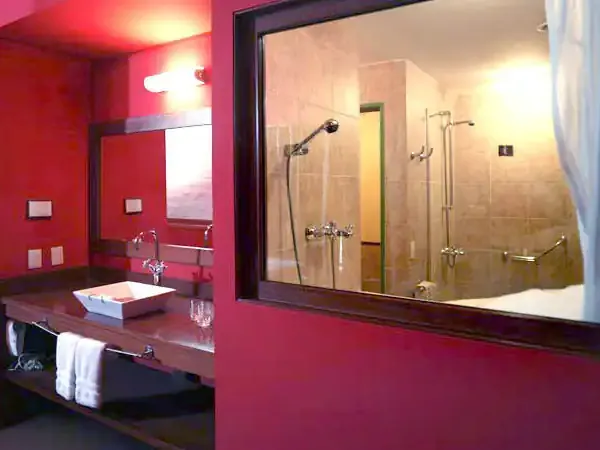 Modern bathroom with vibrant pink walls, rainfall shower, and contemporary fixtures at Los Cerros Boutique Hotel.