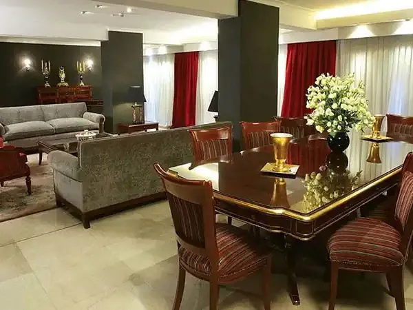 Elegant formal dining room with burgundy chairs, dark wood table, and luxurious furnishings in a diplomatic reception space.