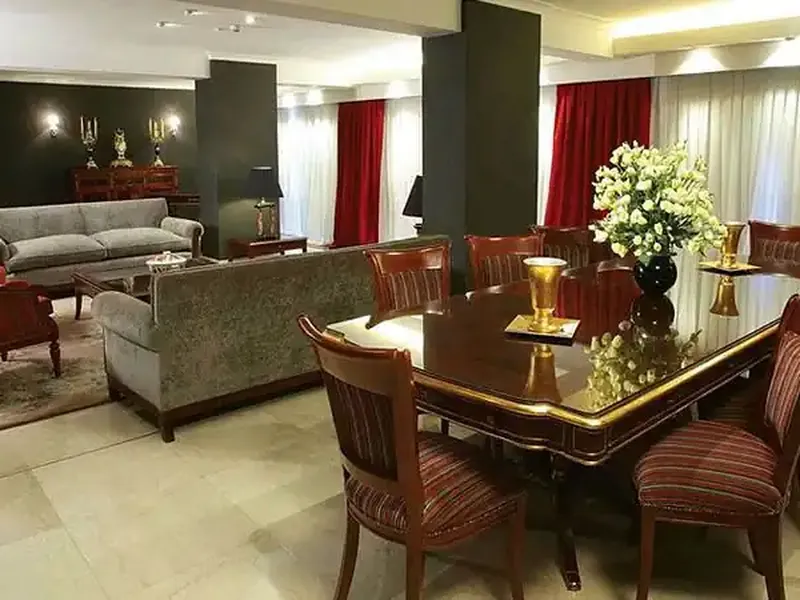Elegant formal dining room with burgundy chairs, dark wood table, and luxurious furnishings in a diplomatic reception space.