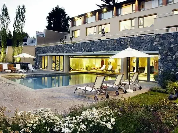 Modern luxury home in Casco with illuminated stone facade, swimming pool, and manicured gardens at dusk.