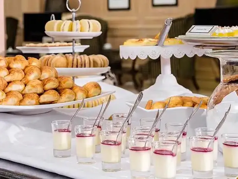 Elegant pastry and dessert buffet display featuring croissants, cookies, and individual mousse cups at a formal diplomatic reception.