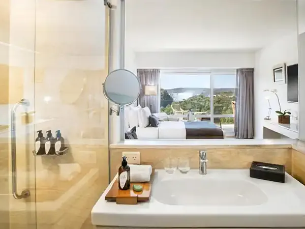 Luxury bathroom at Gran Meliá Iguazú with marble finishes, spa amenities, and views of the Iguazú Falls region from the bedroom beyond.