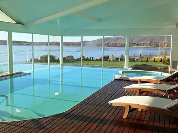 Luxury indoor pool with panoramic lake and mountain views at a Patagonian resort in Elena.