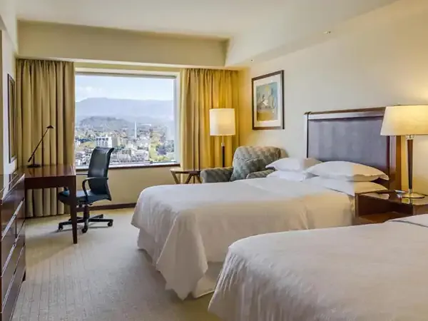 Sheraton Mendoza hotel room with twin beds, city and mountain views through large windows.
