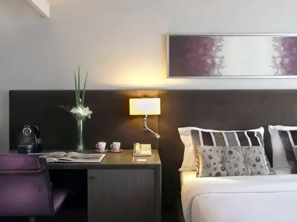 Modern luxury hotel bedroom in Buenos Aires featuring dark wood headboard, purple accents, and contemporary design.