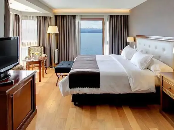 Luxury hotel bedroom with lake and mountain views at Incayal, featuring modern furnishings and panoramic windows overlooking Patagonian waters.