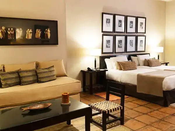 Luxurious hotel suite at Legado Mítico with golden-toned furnishings, African-inspired artwork, and modern amenities blending contemporary comfort with cultural elegance.
