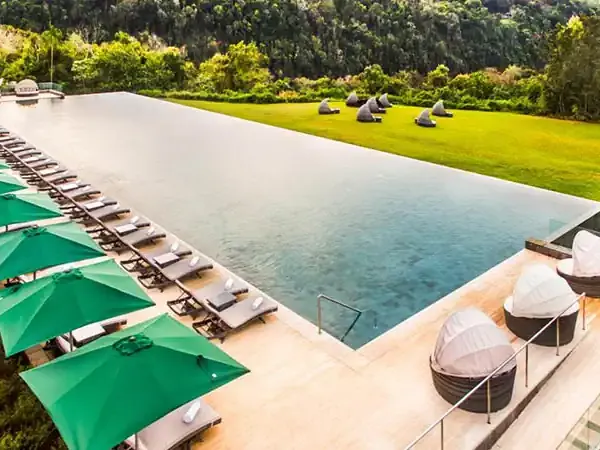 Luxury resort pool at Gran Meliá Iguazú with green umbrellas, loungers, and lush subtropical landscape in Misiones, Argentina.