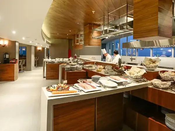 Modern hotel buffet dining area at DoubleTree by Hilton with elegant wood finishes, extensive food displays, and floor-to-ceiling windows.