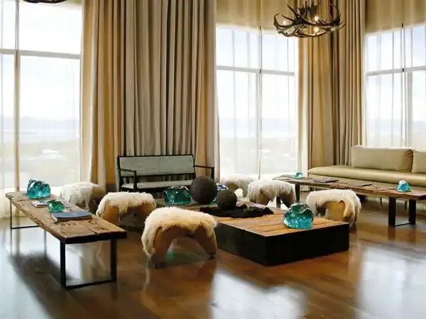 Luxury lodge interior with panoramic windows overlooking Patagonian landscape, featuring rustic wooden tables and contemporary furnishings.