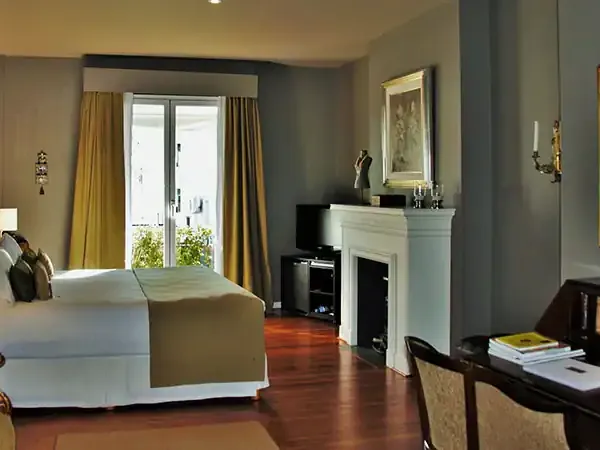 Elegant hotel suite bedroom with fireplace, hardwood floors, and modern furnishings in a luxurious Argentine accommodation.