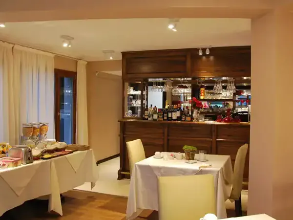 Elegant dining room at El Chaltén Suites with white tablecloths, wooden bar, and warm ambient lighting.