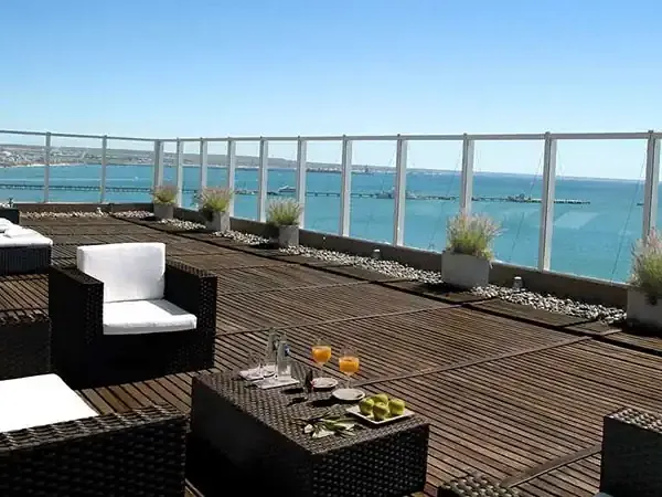 Luxury rooftop terrace overlooking turquoise waters in Puerto Madryn with modern furniture and coastal views.