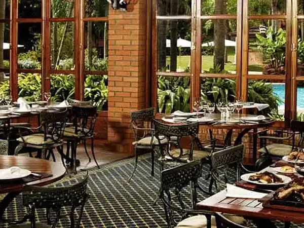Elegant dining room at Iguazú Grand with floor-to-ceiling windows overlooking lush gardens and pool.