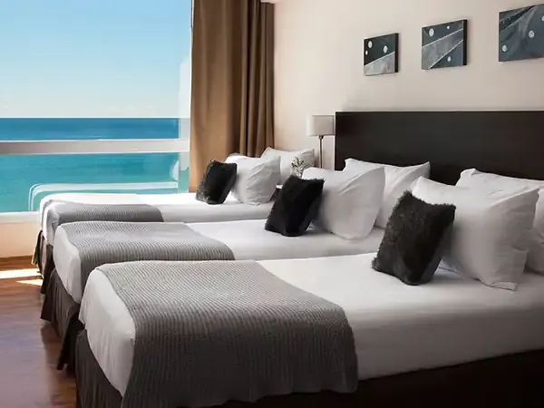 Luxury beachfront hotel room with multiple beds, ocean views, and modern amenities in Puerto Madryn.
