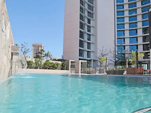 Modern swimming pool at DoubleTree by Hilton hotel surrounded by residential towers in an urban development.