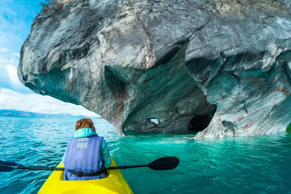 Kayaker paddling toward the marble caves with turquoise waters at Capillas de Mármol, Patagonia.