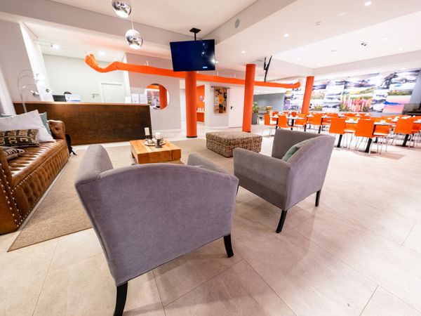 Modern hotel lobby in Tierra del Fuego featuring purple armchairs, orange structural columns, and bright contemporary design.