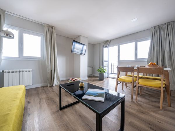 Modern bright apartment in Tierra del Fuego with yellow accents, wooden flooring, and panoramic windows overlooking the landscape.