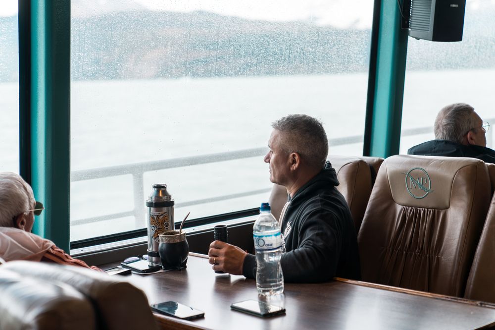 Passengers enjoy views of snow-covered mountains and glaciers from a luxury coach cabin during a Patagonian sightseeing tour near El Calafate.