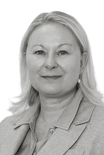 Portrait of a person with shoulder-length blonde hair, wearing a light-colored blazer and shirt, on a plain white background.