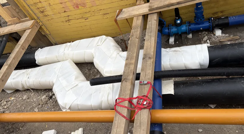 Baustellensituation mit verlegten Versorgungsleitungen, isolierten Rohrsystemen und technischen Anschlüssen für die Energie- und Gebäudetechnik. Die Installation dient der sicheren Verteilung von Wärme, Wasser oder anderen Medien innerhalb einer technischen Infrastruktur.