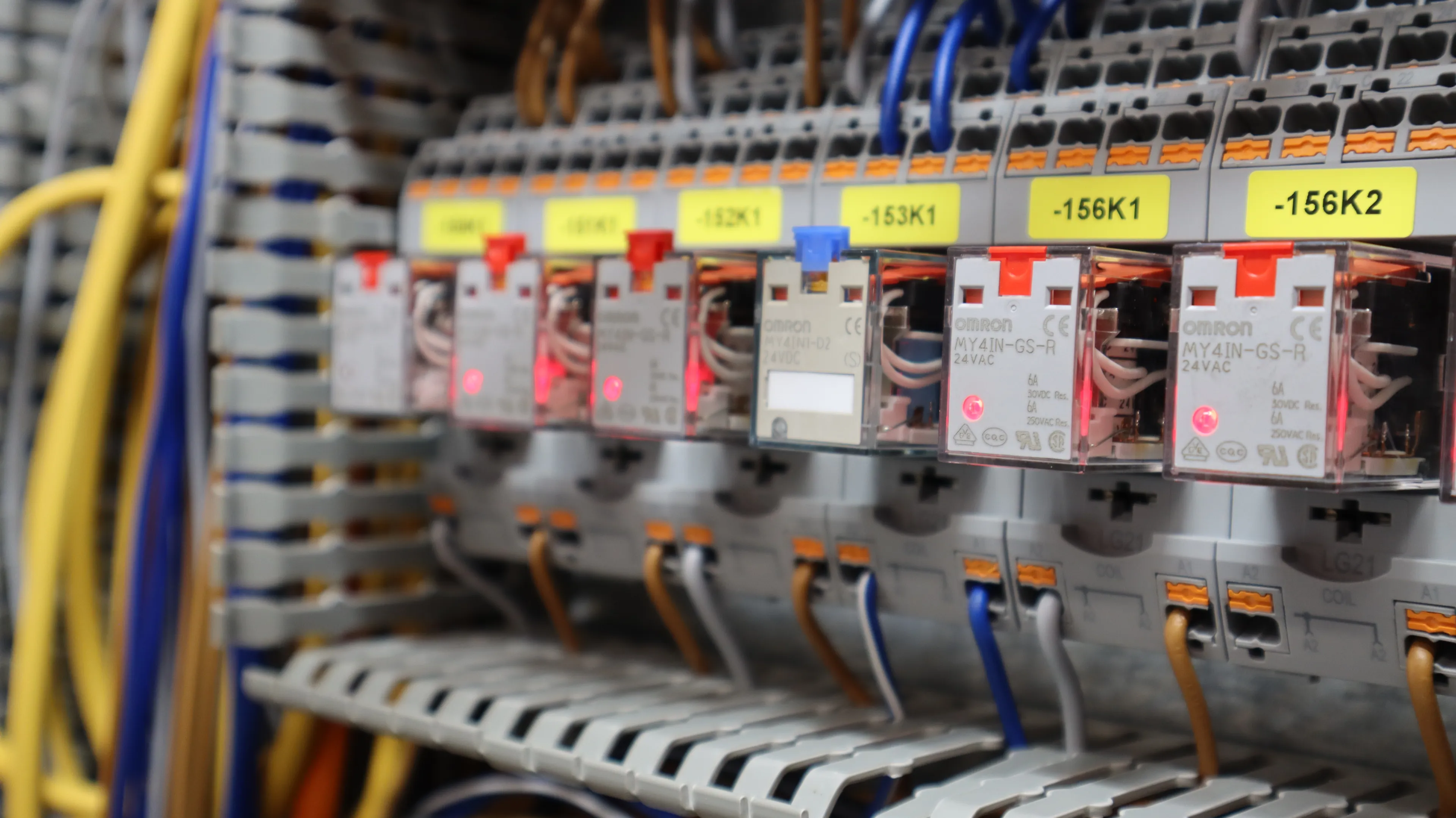 Detailansicht eines elektrischen Schaltschranks mit Relaismodulen, Klemmen und sauber verlegten Kabeln. Die industrielle Steuerungstechnik ist übersichtlich beschriftet und fachgerecht verdrahtet.