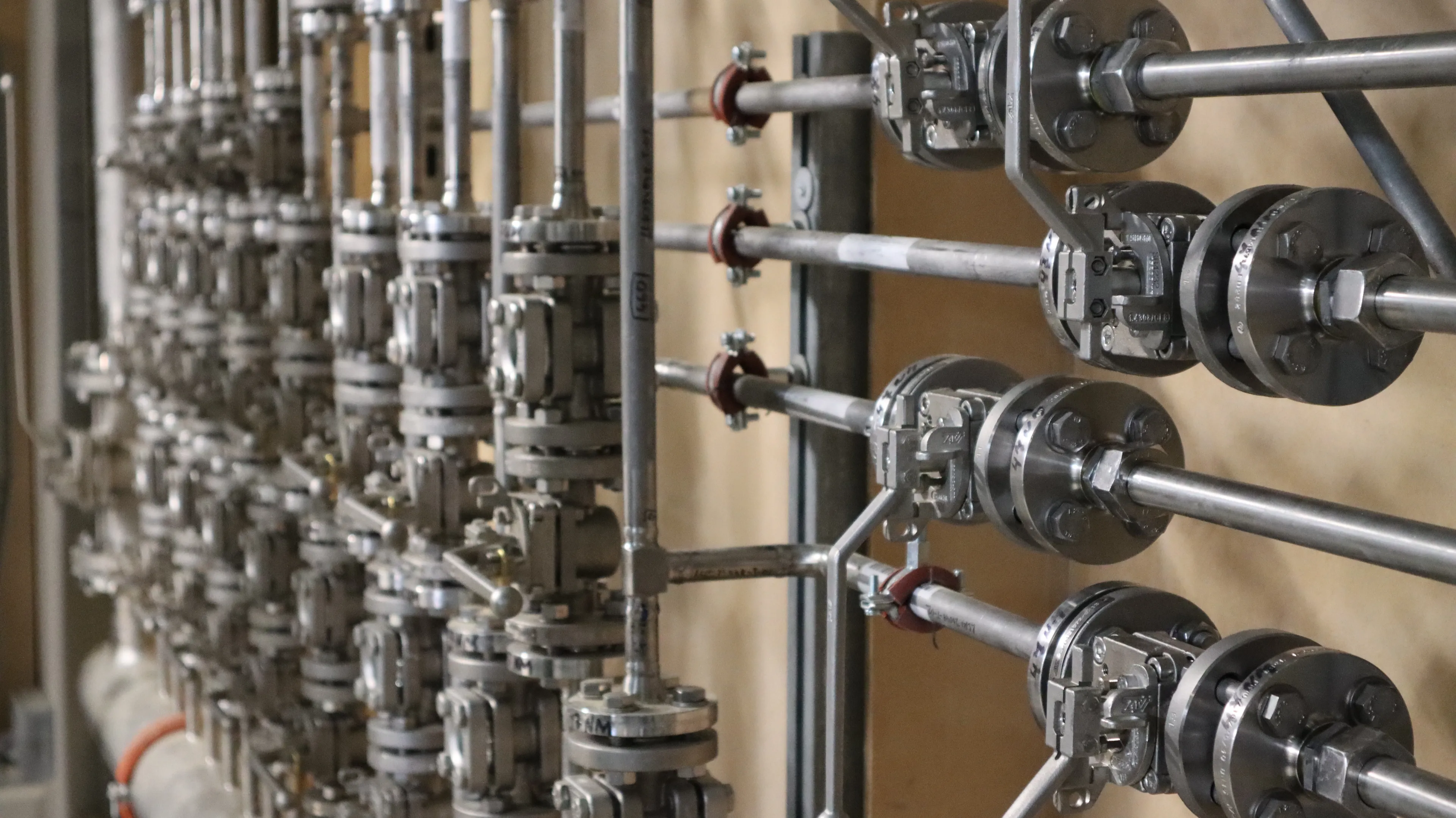 Industrielle Mess-, Steuer- und Regeltechnik mit zahlreichen Armaturen, Ventilen und Sensoren entlang eines Rohrleitungssystems. Die technische Anlage ermöglicht die präzise Überwachung und Steuerung von Prozessen in der Energie-, Gebäude- und Versorgungstechnik.