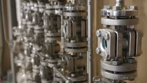 Industrielle Rohrleitungsanlage mit mehreren Edelstahlventilen und Absperrarmaturen. Die Komponenten sind Teil einer technischen Prozess- oder Energieanlage und ermöglichen die präzise Steuerung von Medienströmen.
