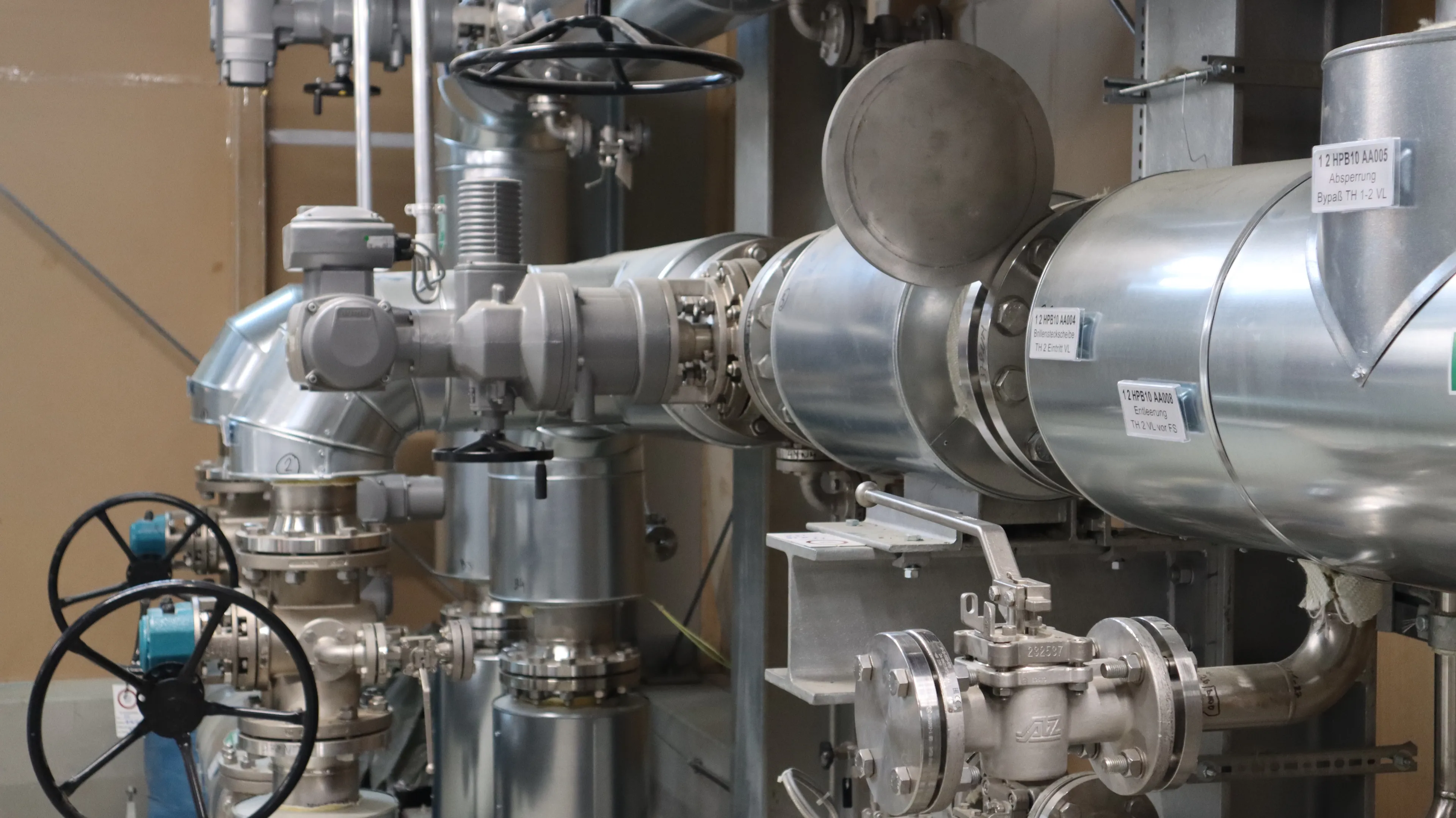 Technische Anlagenkomponenten mit isolierten Rohrleitungen, Regelventilen und Armaturen in einer industriellen Energie- oder Versorgungstechnik. Die Anlage dient der sicheren Steuerung, Überwachung und Verteilung von Medien innerhalb komplexer technischer Systeme.