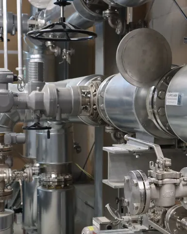 Technische Anlagenkomponenten mit isolierten Rohrleitungen, Regelventilen und Armaturen in einer industriellen Energie- oder Versorgungstechnik. Die Anlage dient der sicheren Steuerung, Überwachung und Verteilung von Medien innerhalb komplexer technischer Systeme.