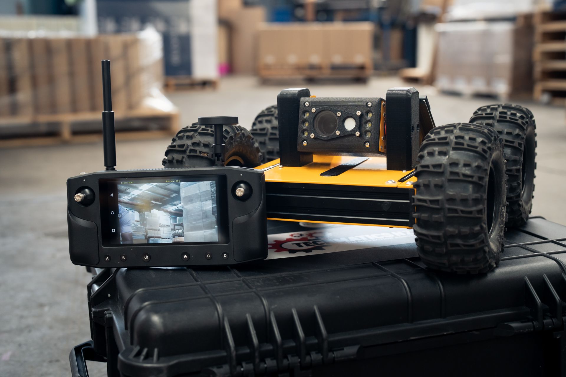 Techmatics inspection robot on a transport case beside its handheld controller showing a live camera feed