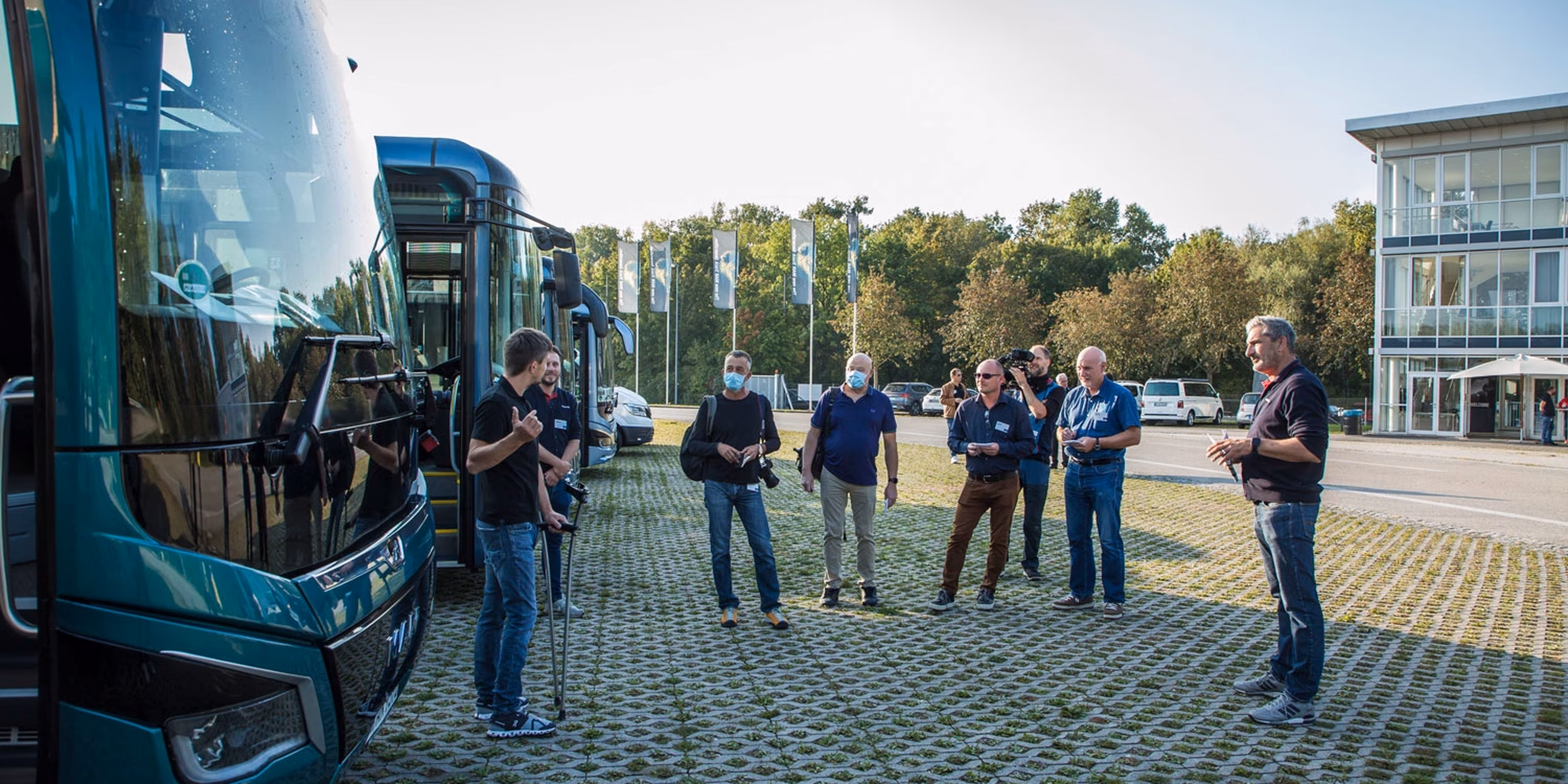 6 personen unterhalten sich vor 2 reisebussen