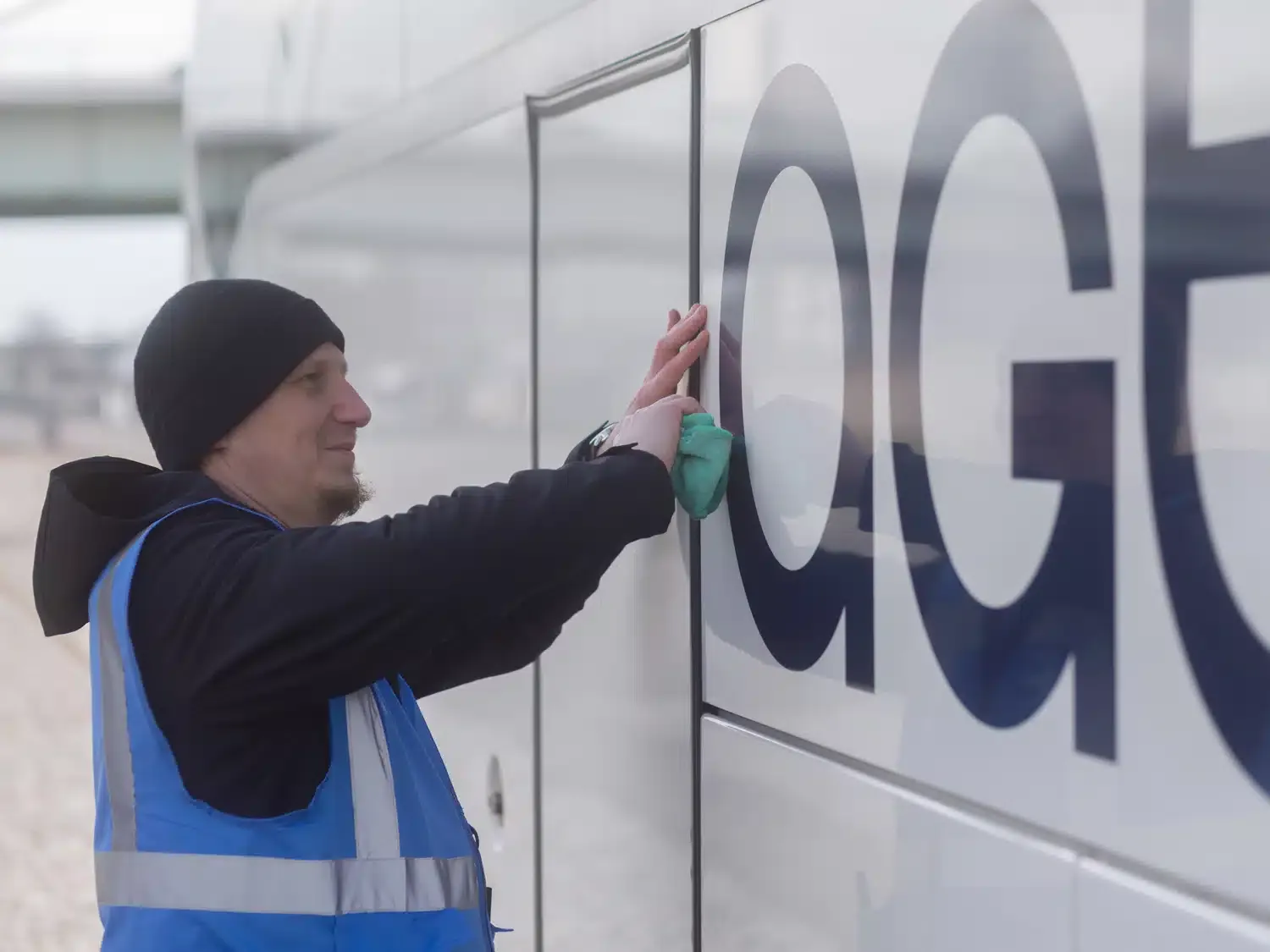 Mitarbeiter putzt Busbranding