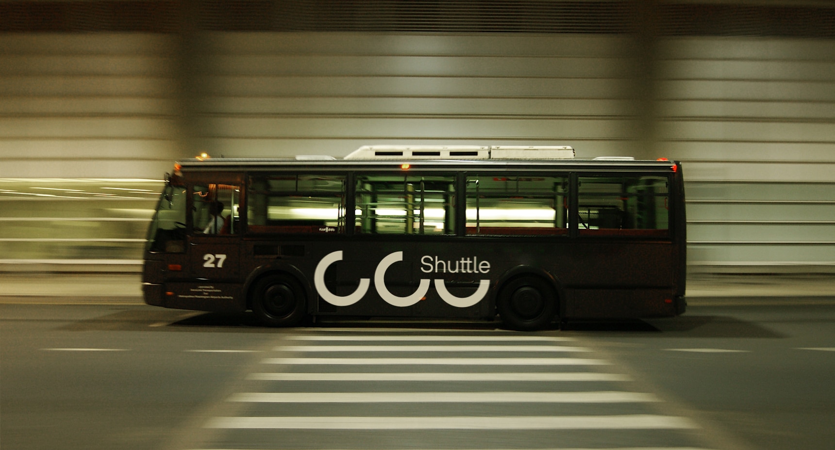 Schwarzer Shuttlebus fährt mit Bewegungsunschärfe durch eine moderne Verkehrsanlage.
