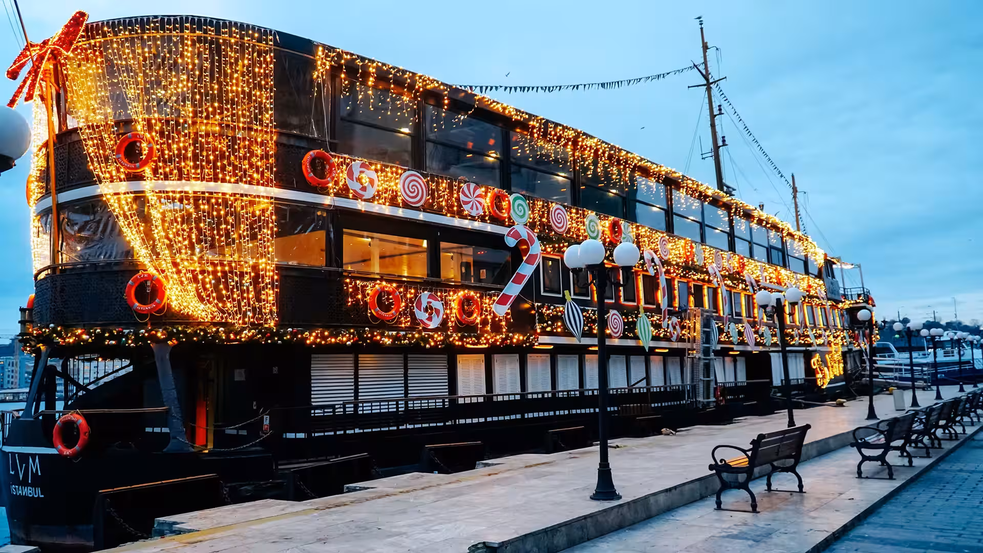 Weihnachtlich geschmücktes Ausflugsschiff mit Lichtervorhang und bunter Deko am Kai in Istanbul.