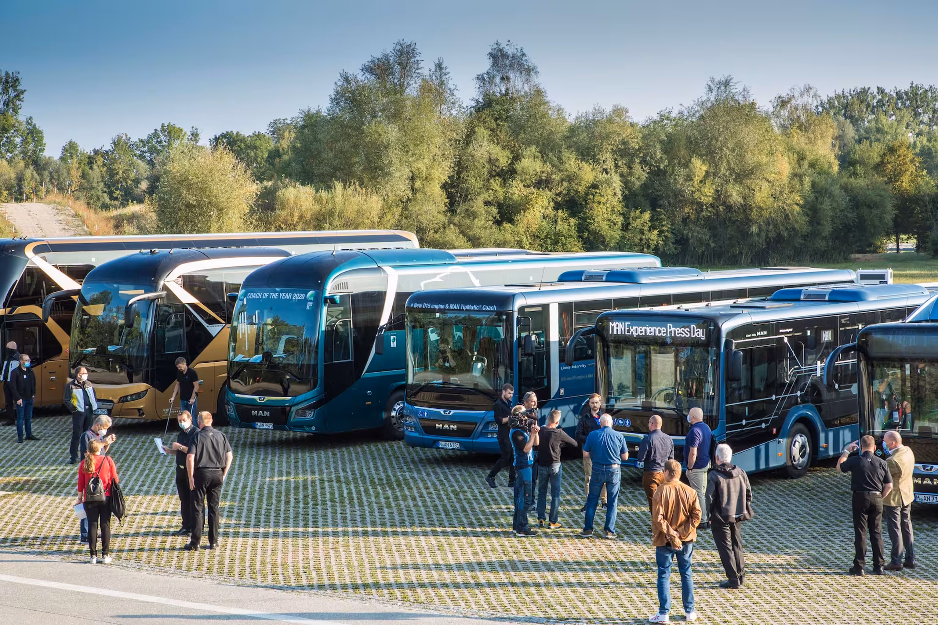 Teilnehmende einer Busfachveranstaltung besichtigen verschiedene Busmodelle auf dem Ausstellungsgelände.