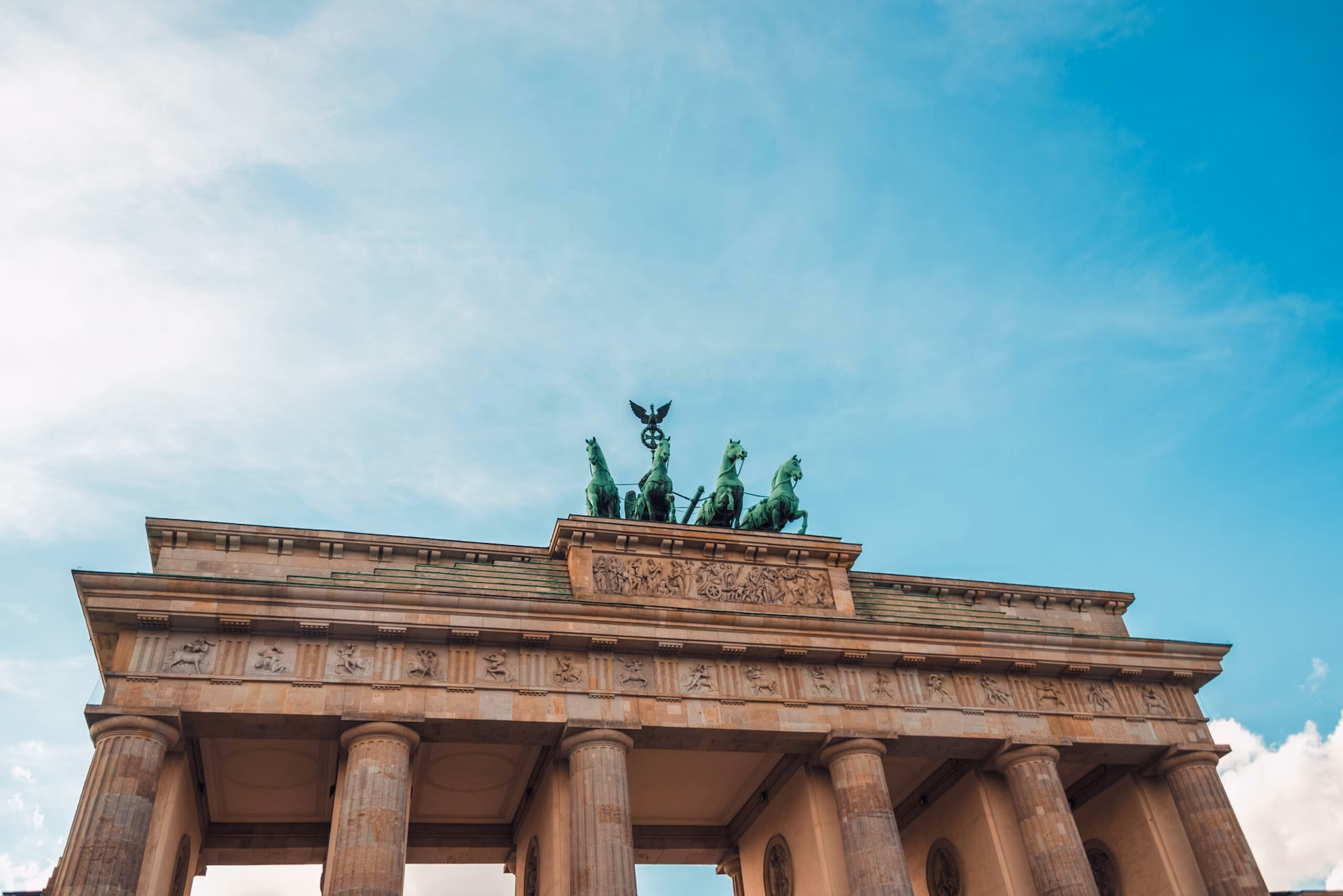 Das Brandenburger Tor vor blauem Himmel mit der ikonischen Quadriga auf der Spitze.