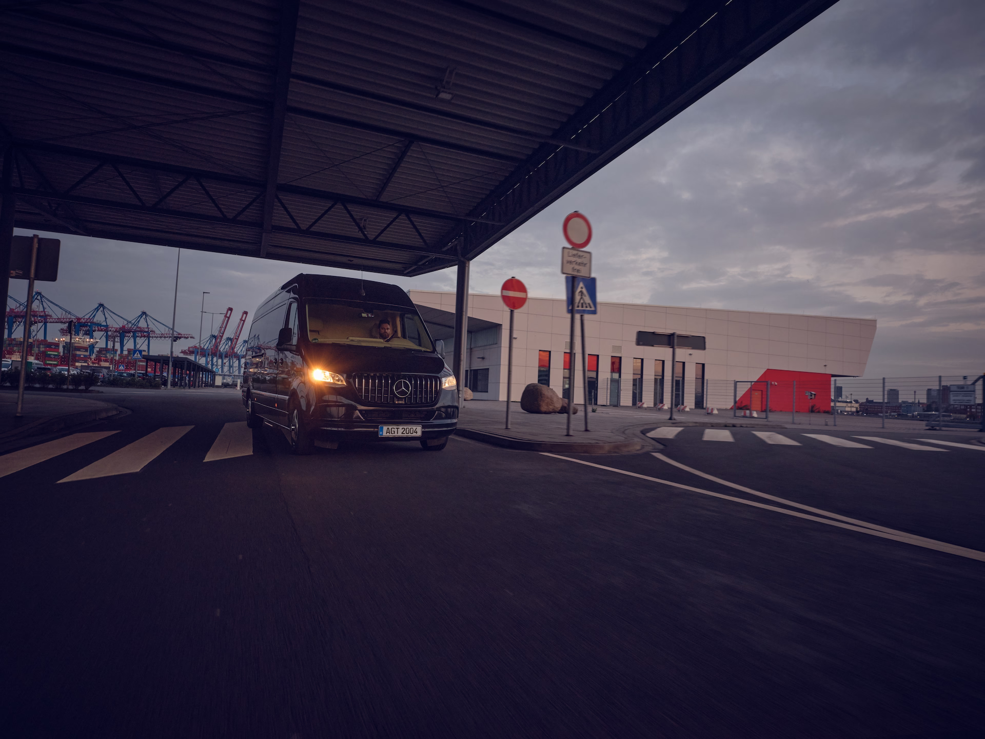 Schwarzer Kleinbus fährt durch ein Hafengelände