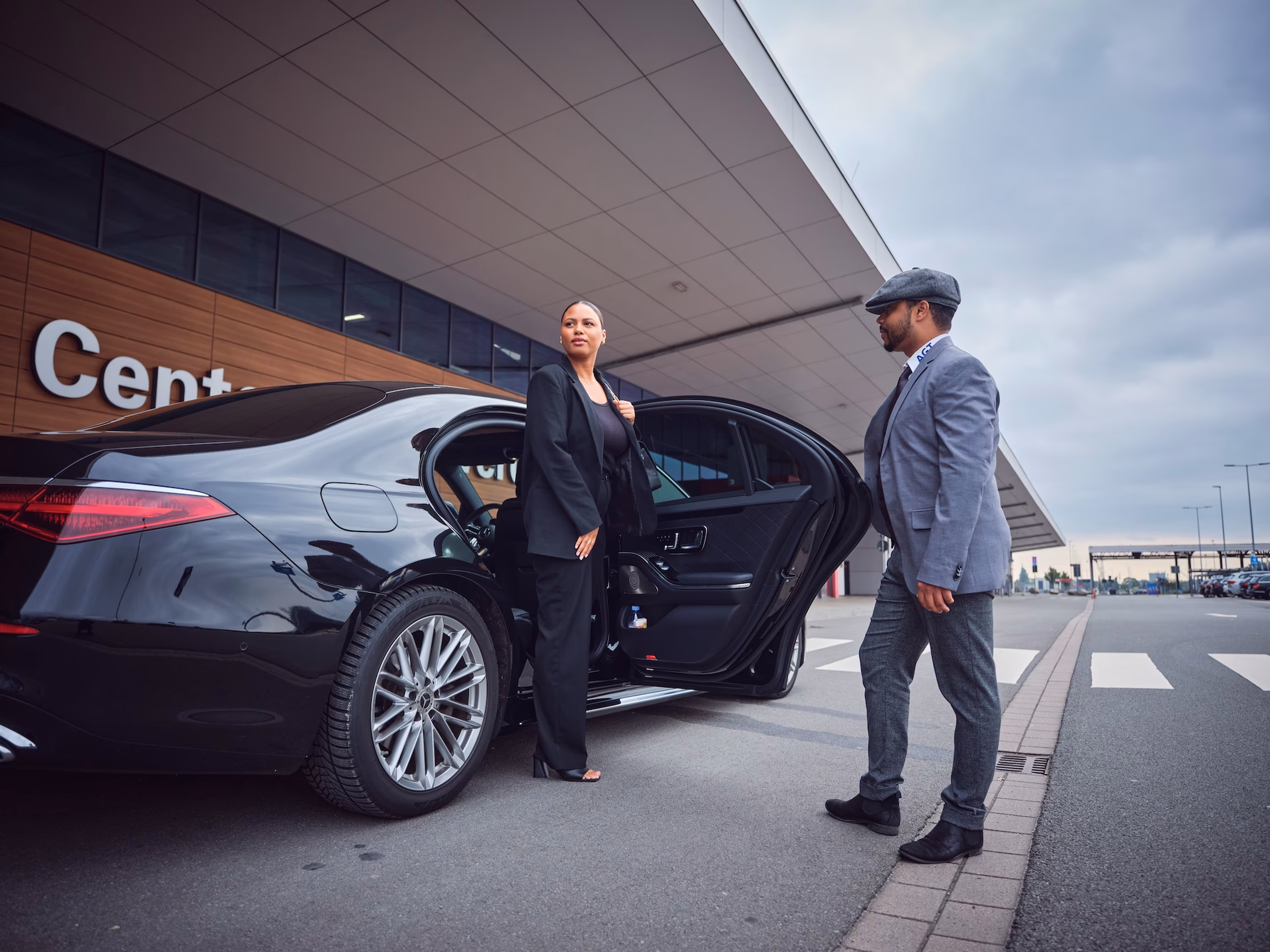 Geschäftskundin steigt aus einer Limousine aus, während der Chauffeur sie am Cruise Center empfängt.