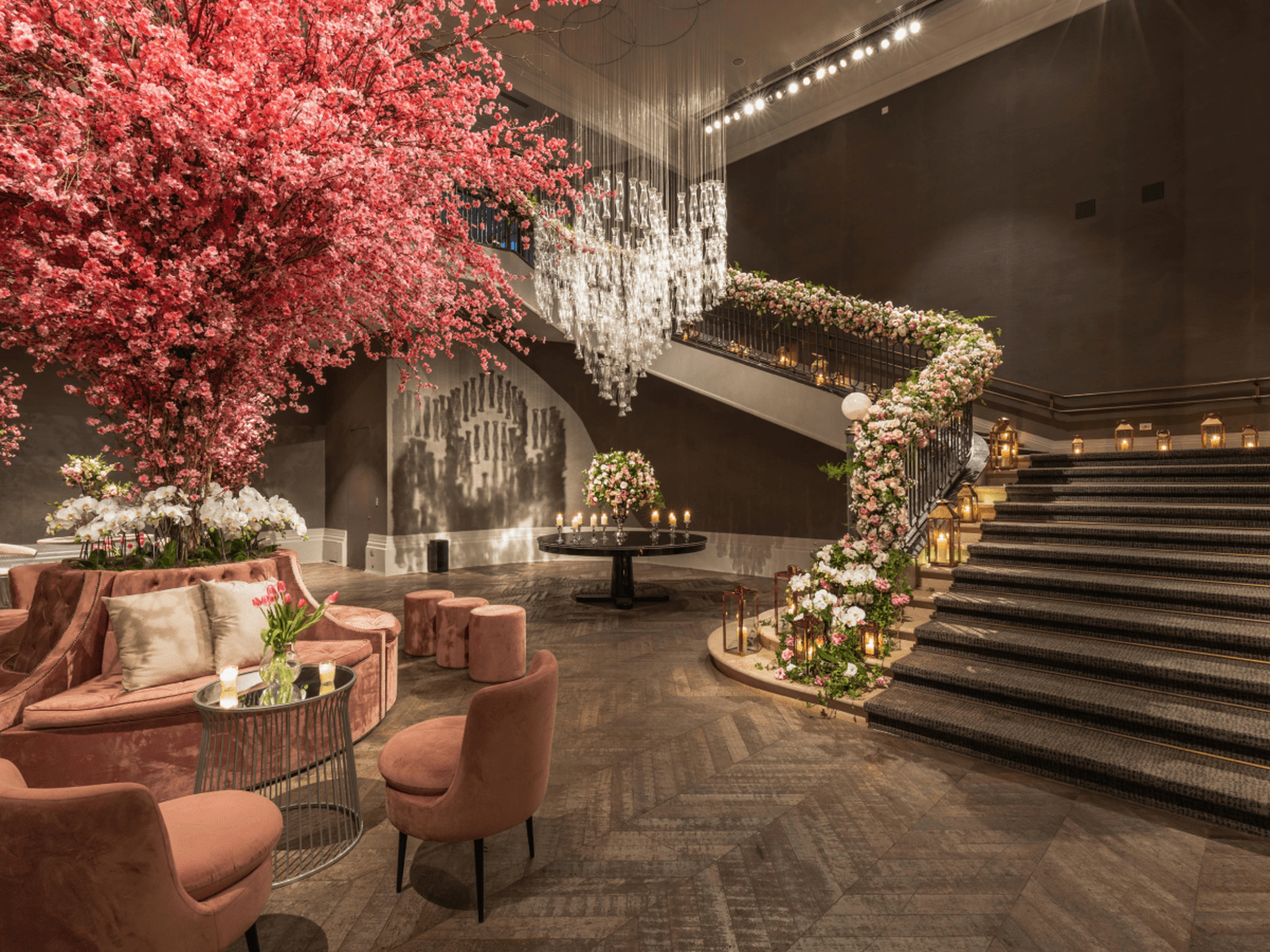 Hotel lobby with a seating area, lots of flowers and a staircase