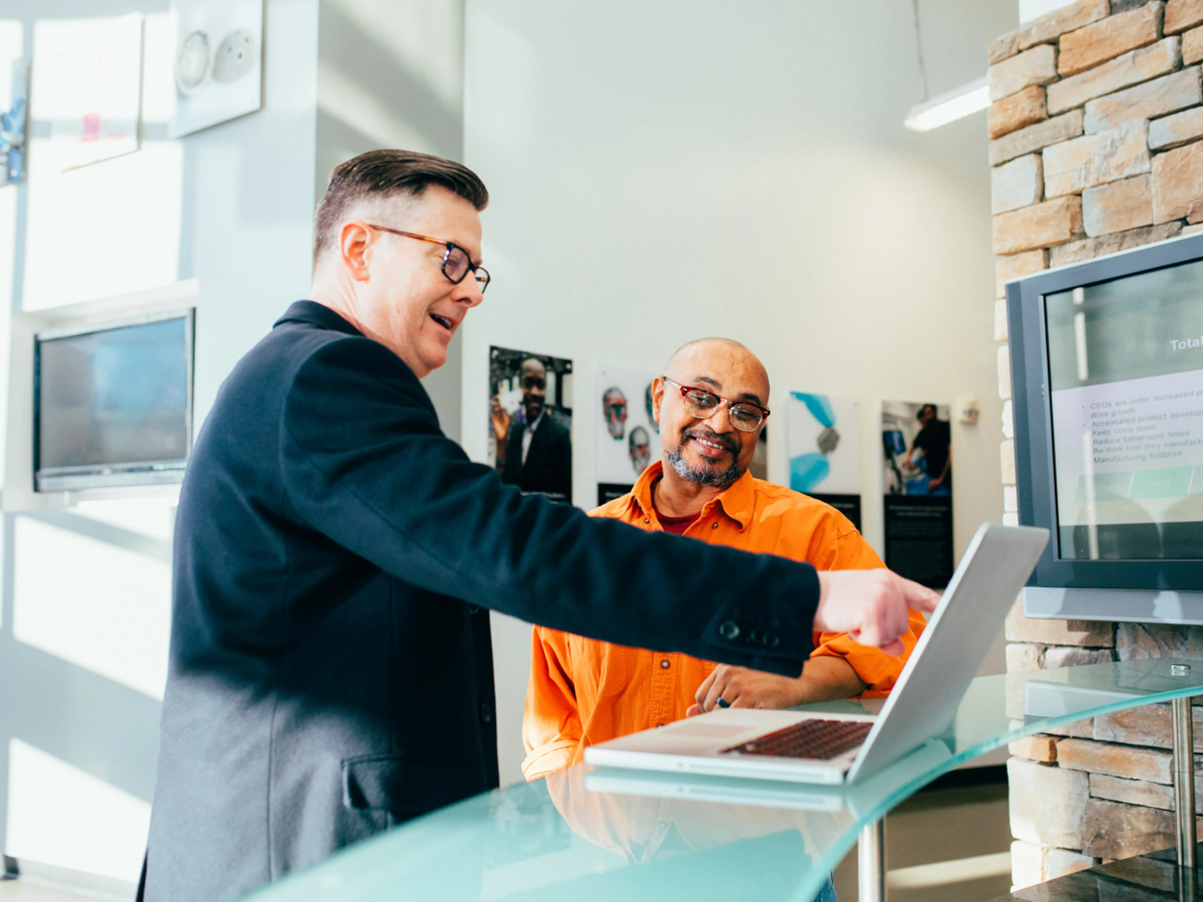 Two people looking a metrics on a laptop screen at the front desk
