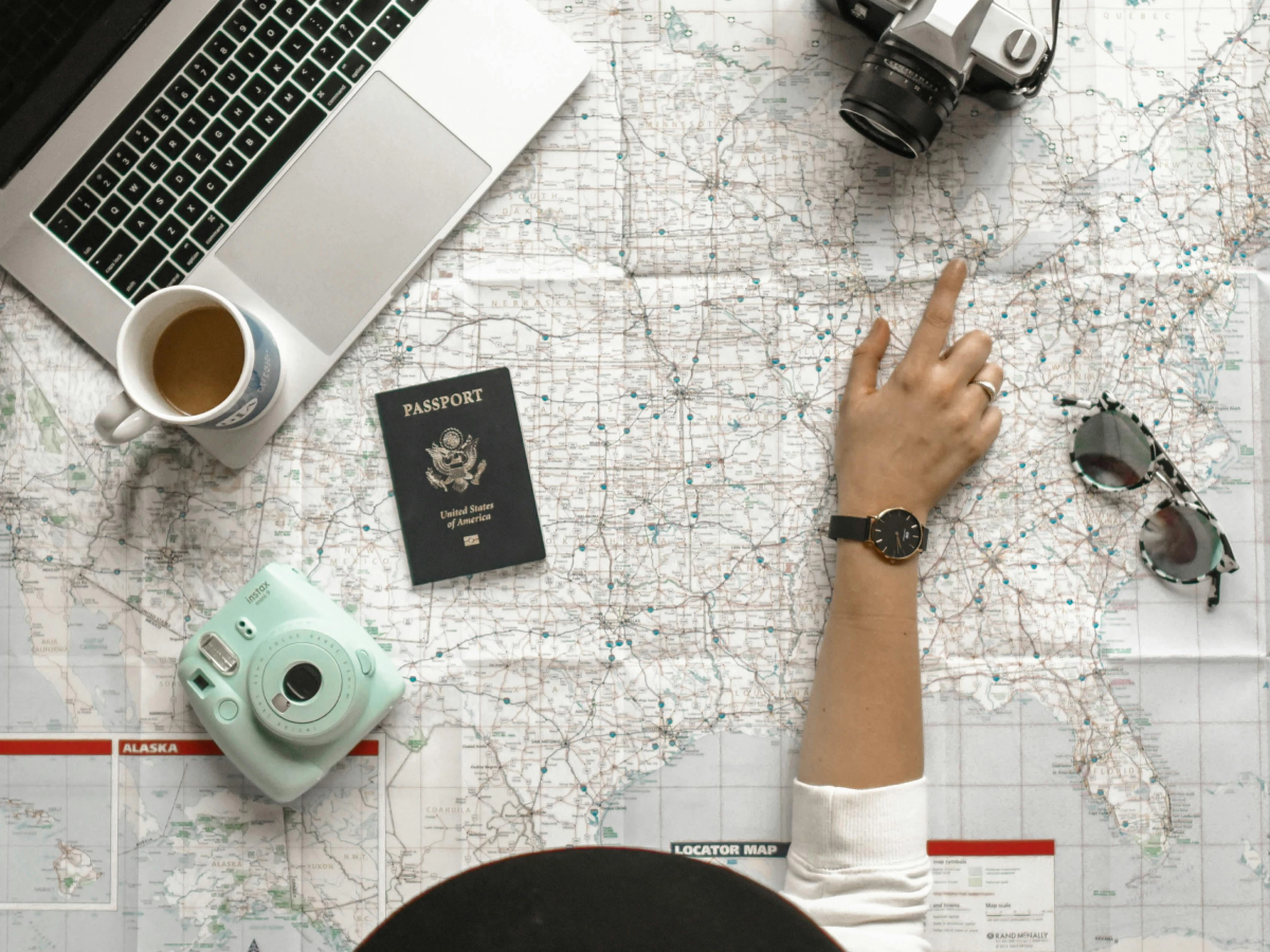 Map of the world with a laptop, camera, passport, sunglasses and coffee