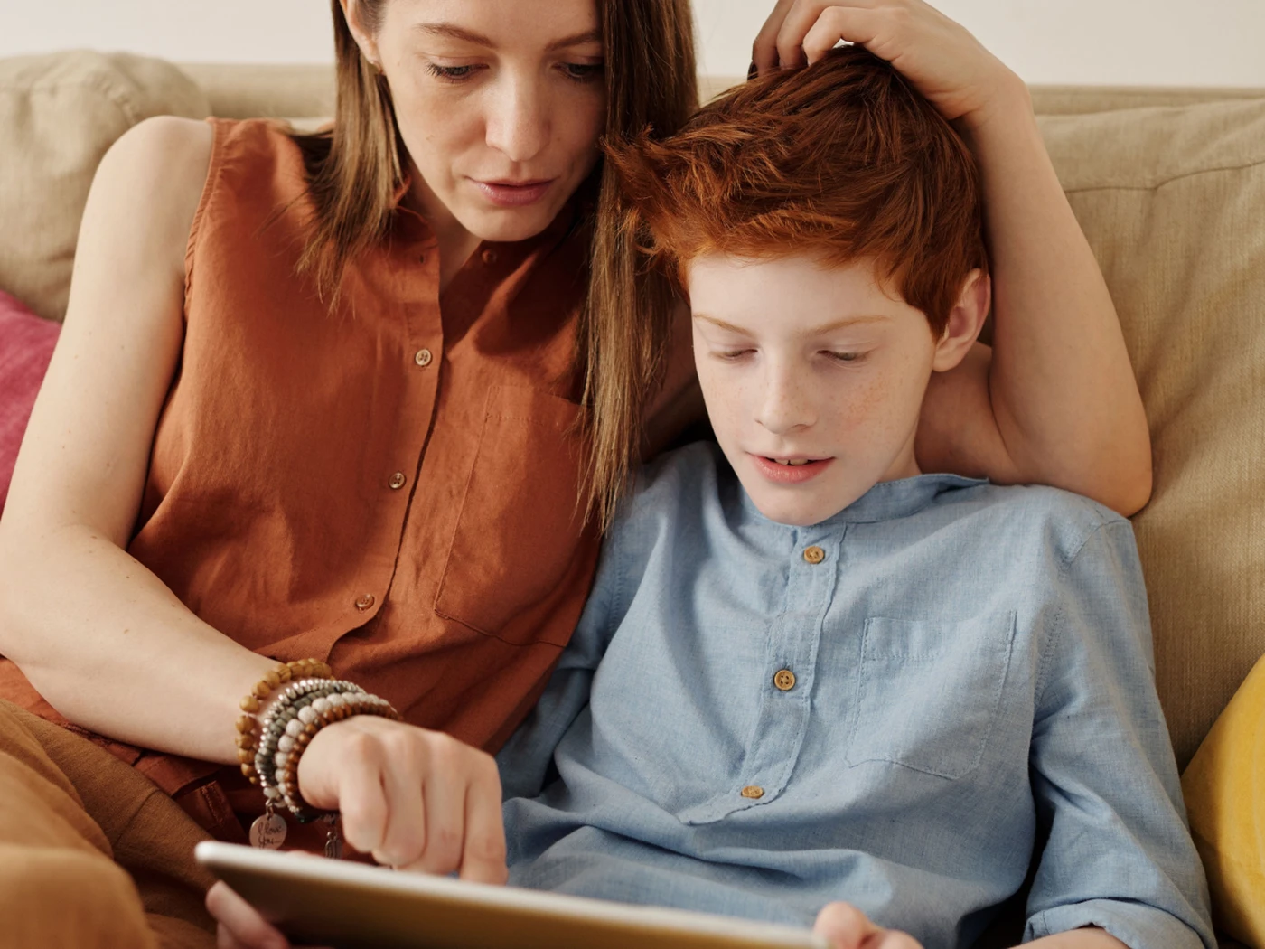 mother and child sitting on the couch, looking at a tablet together