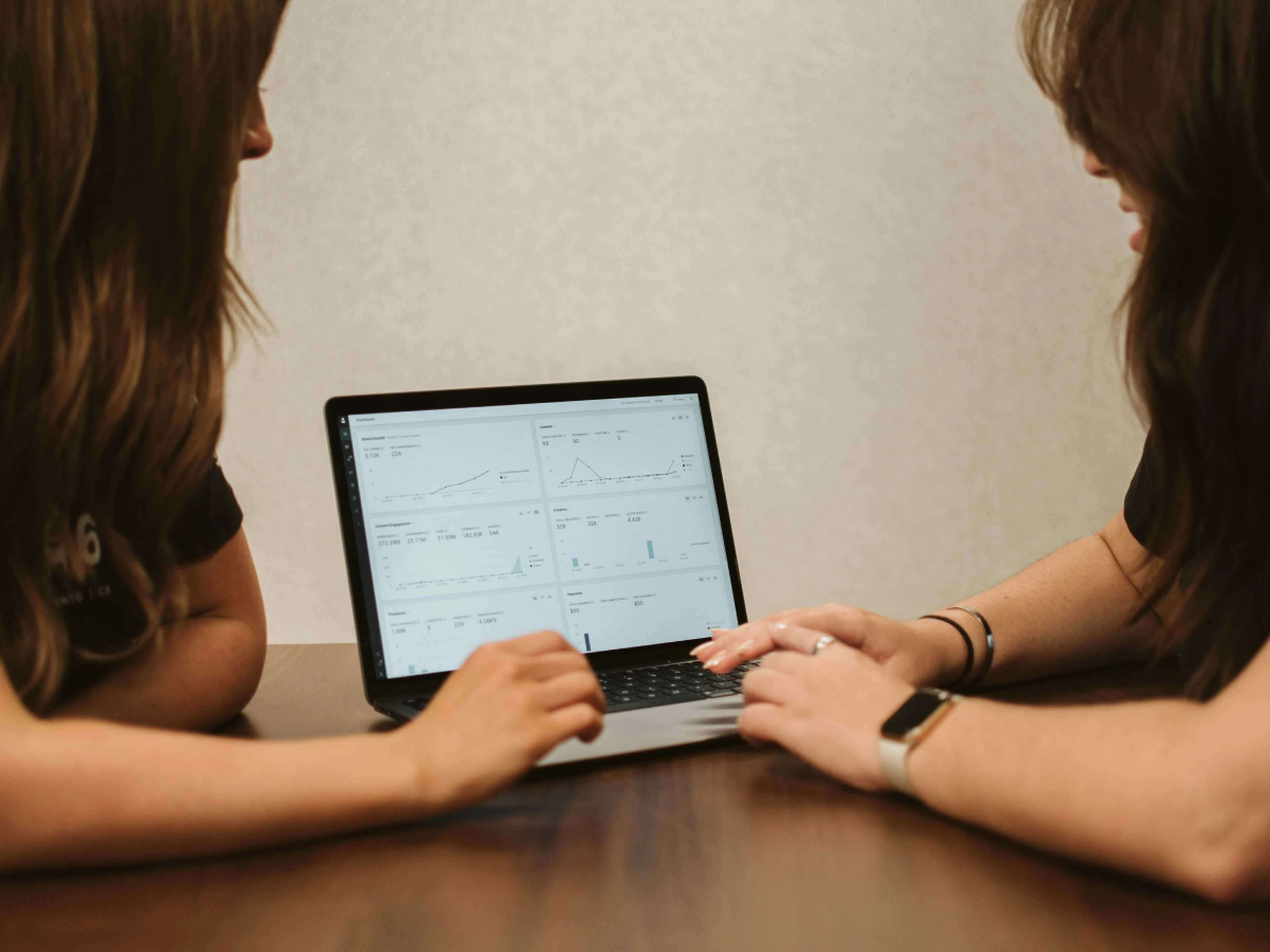 Two women looking at graphs on a screen